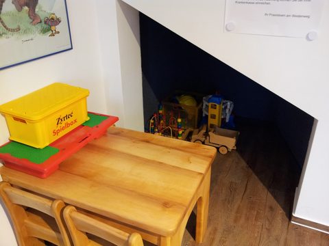Spielecke mit Kindertisch, Spielzeugkiste und Holzspielzeug