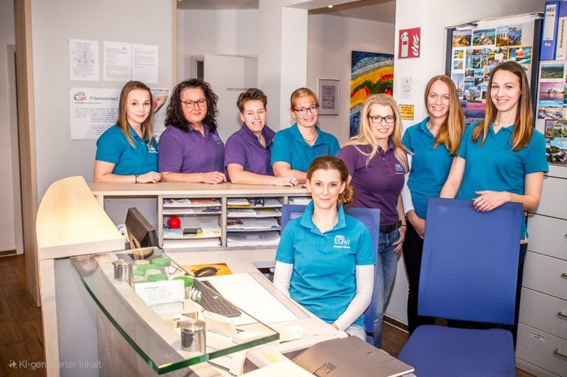 Das Team der Praxis am Weidenweg in Arbeitskleidung am Empfangstresen